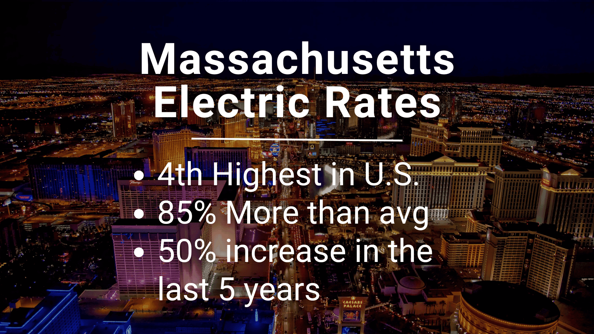 Massachusetts electric rates nighttime cityscape view showing illuminated buildings and busy streets.