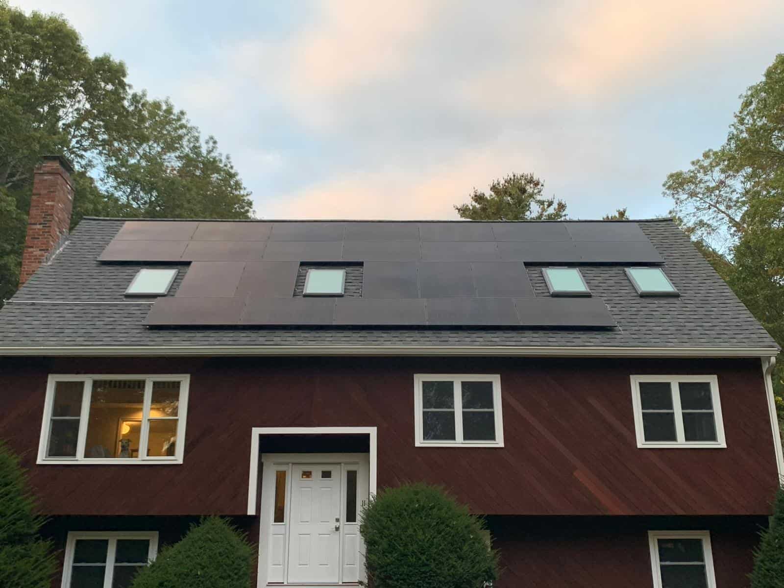 Residential home with a full-width roof-mounted solar panel system integrated into an asphalt shingle roof, designed to maximize solar energy production, reduce electric bills, and deliver long-term solar savings for a New England homeowner through a clean, efficient residential solar installation.