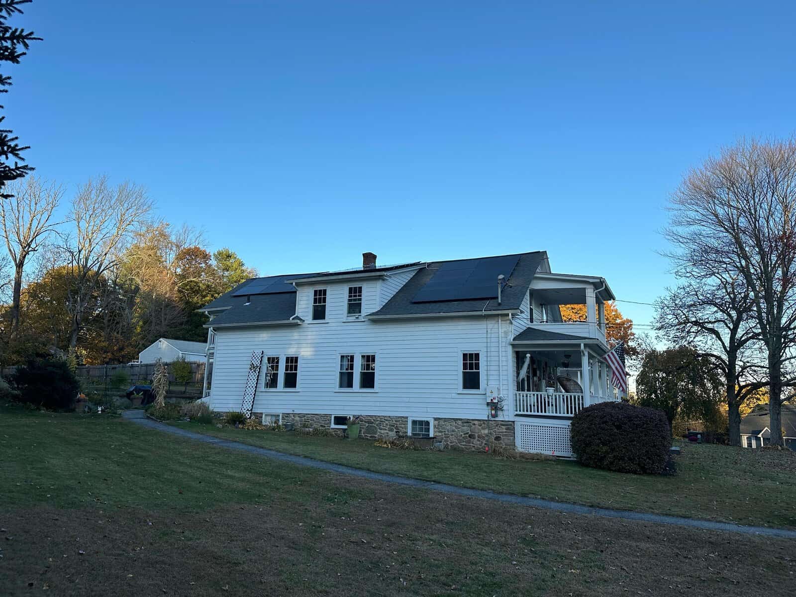 White New England farmhouse with multiple roof-mounted solar panel arrays, showcasing a residential solar installation designed to lower electric bills, improve energy efficiency, and generate long-term solar savings for the homeowner.