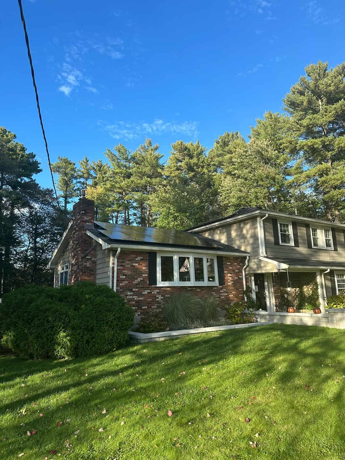 Front exterior of a New England home with rooftop solar panels, showcasing residential solar installation, clean energy production, and long-term solar savings for homeowners.