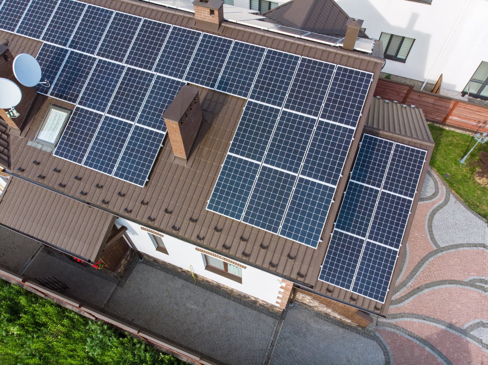 Aerial view of solar panels installed across the brown tiled roof of a residential home, maximizing energy production and showcasing a strong commitment to clean, renewable power.