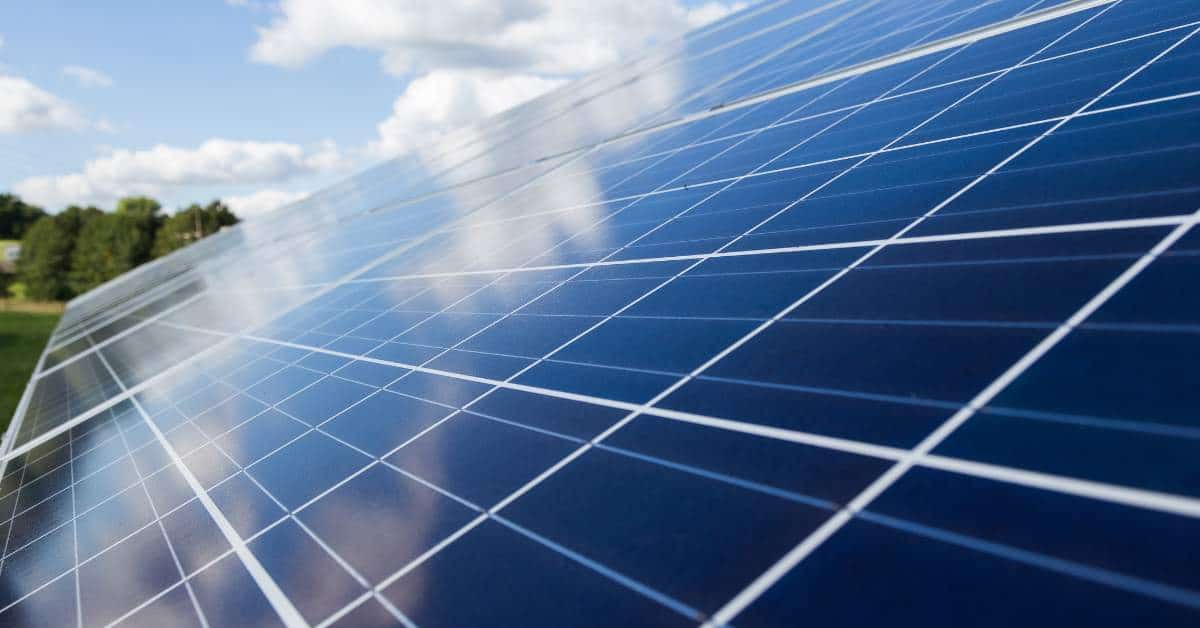 Solar panels connected to each other with inverters, blue sky background, with sun shining on them