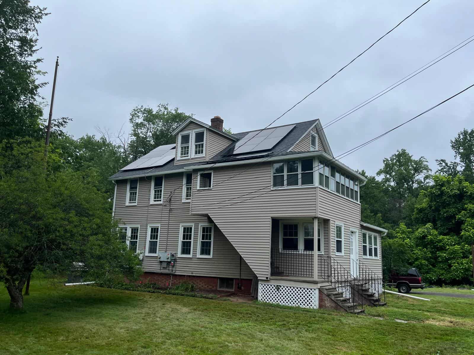 Solar panels installed on the roof of a multi-story house surrounded by greenery, demonstrating residential solar energy solutions for eco-friendly power generation.