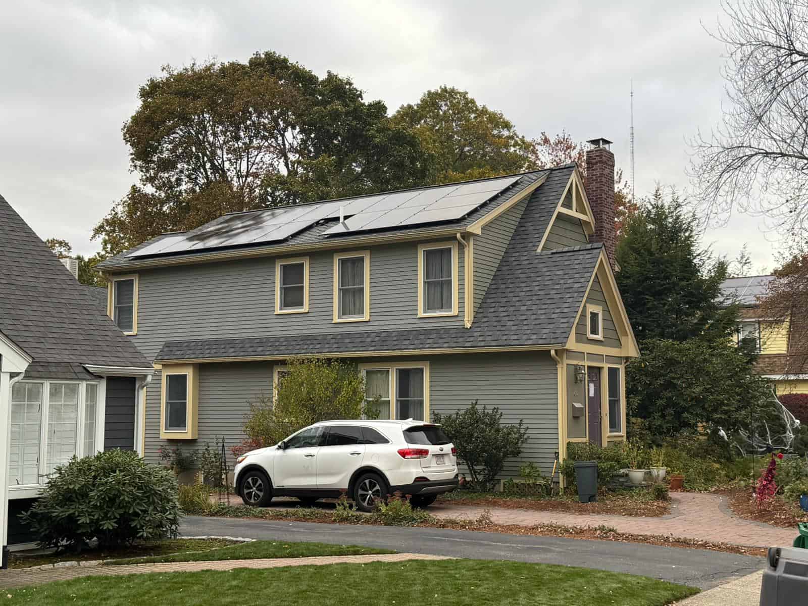 Two-story New England home with gray siding and a pitched roof fitted with residential solar panels, showcasing a clean solar installation designed to lower electric bills, improve energy efficiency, and deliver long-term solar savings for homeowners.