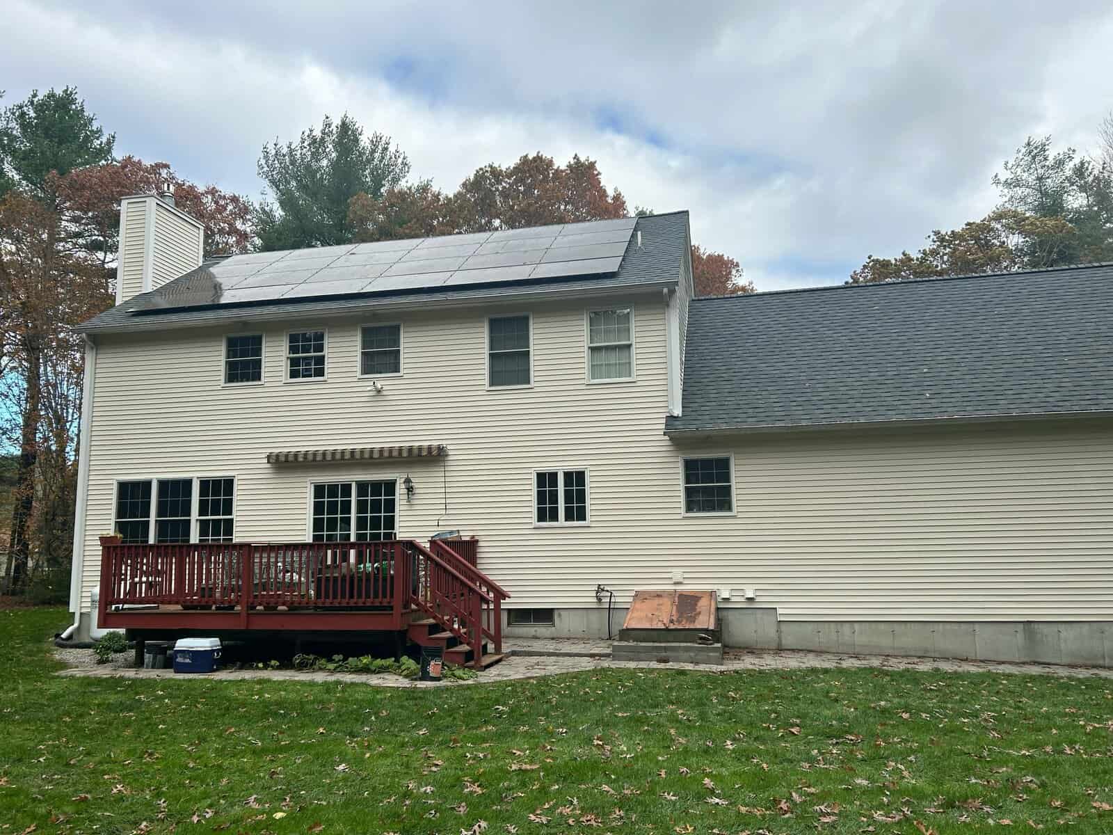 Backyard view of a New England home with rooftop solar panels, showcasing residential solar installation, long-term solar savings, and clean energy powering the home.