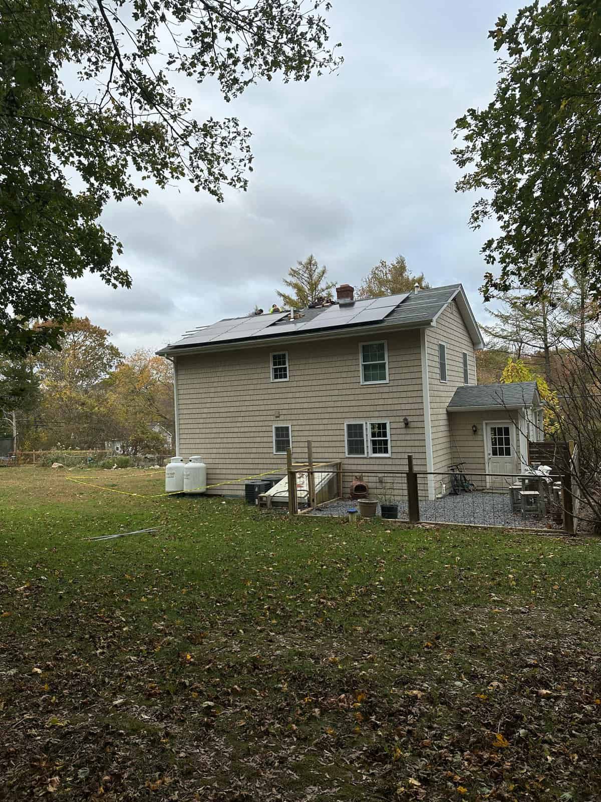 Two-story New England home with rooftop solar panels installed, showcasing residential solar installation for energy savings, lower electric bills, and long-term home value in a suburban setting.