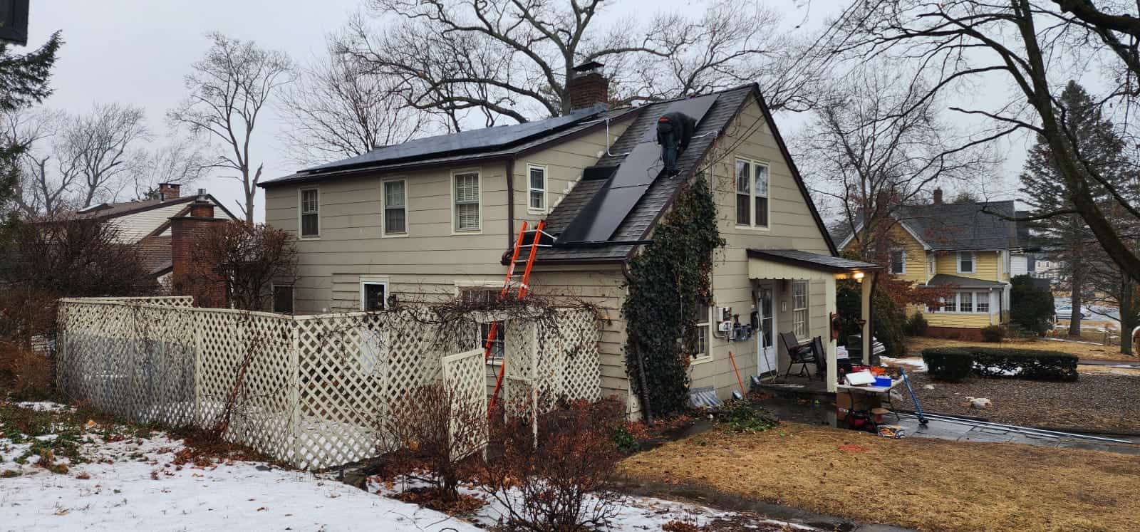 Newly installed solar panels on the roof of a residential house in a suburban neighborhood, showcasing solar energy system installation during late fall.
