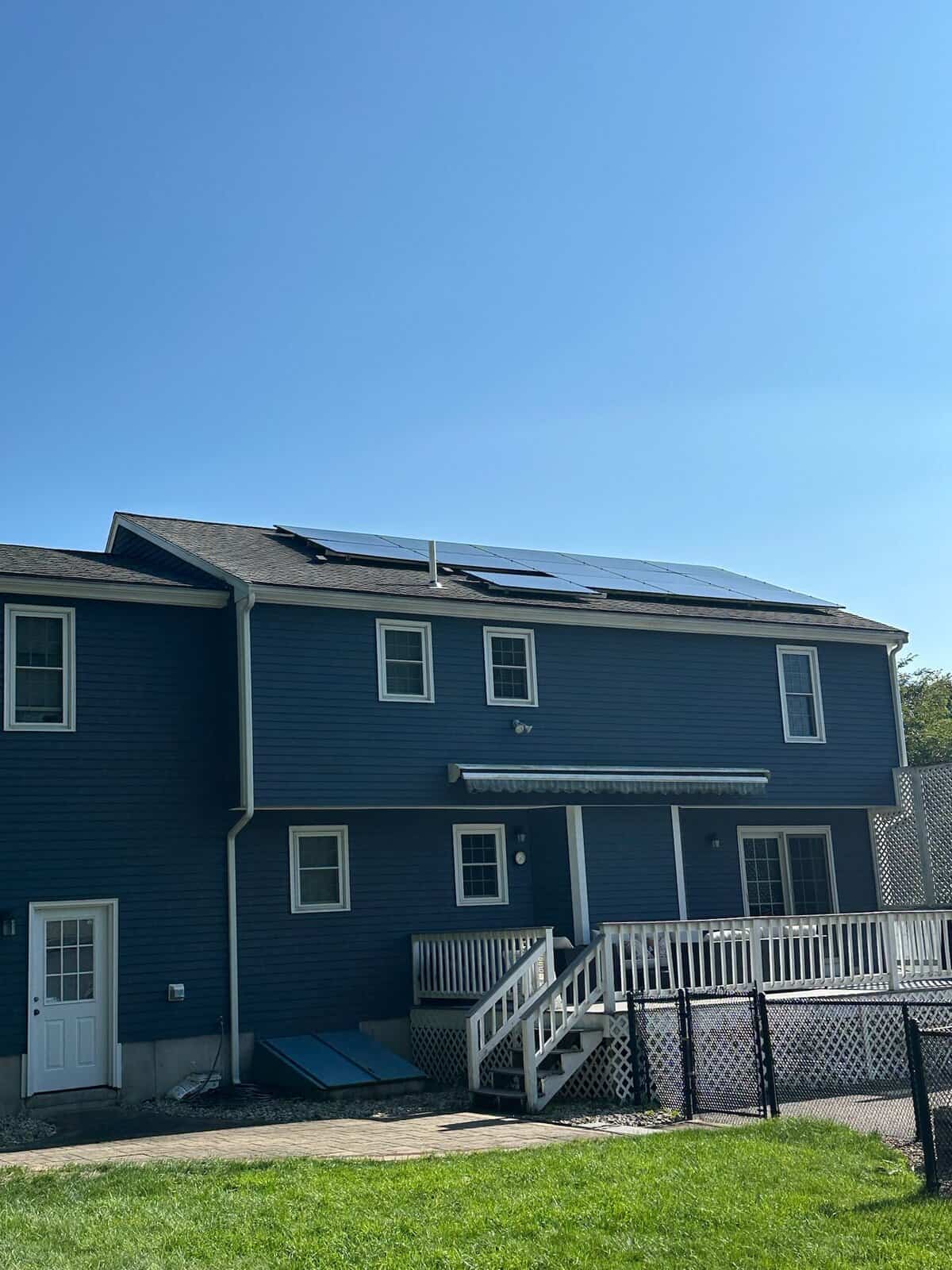 Dark blue two-story house with rooftop solar panels, helping lower energy costs with clean renewable power.