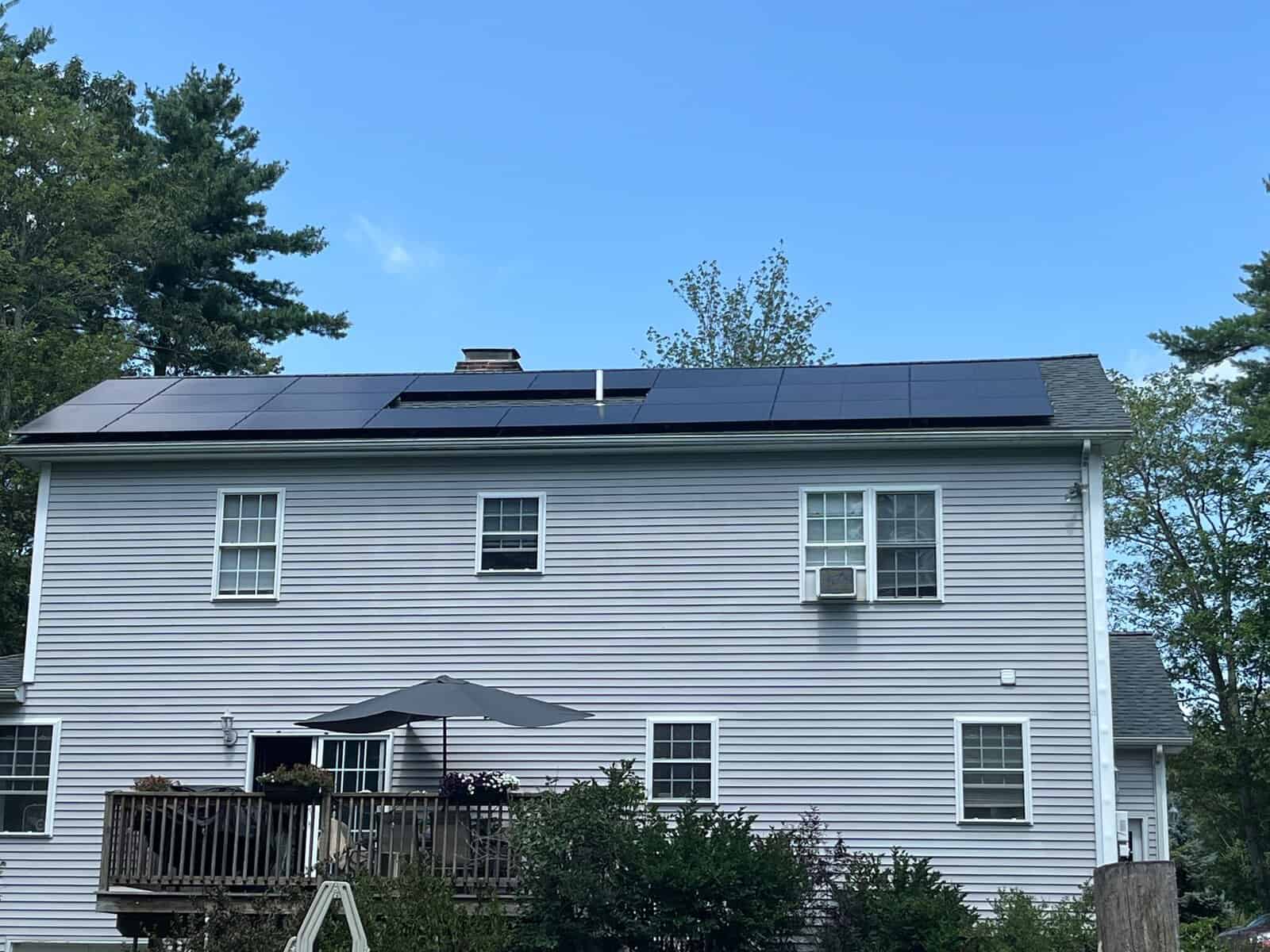 Two-story gray house with sleek black solar panels installed on the roof, providing clean energy and long-term savings.