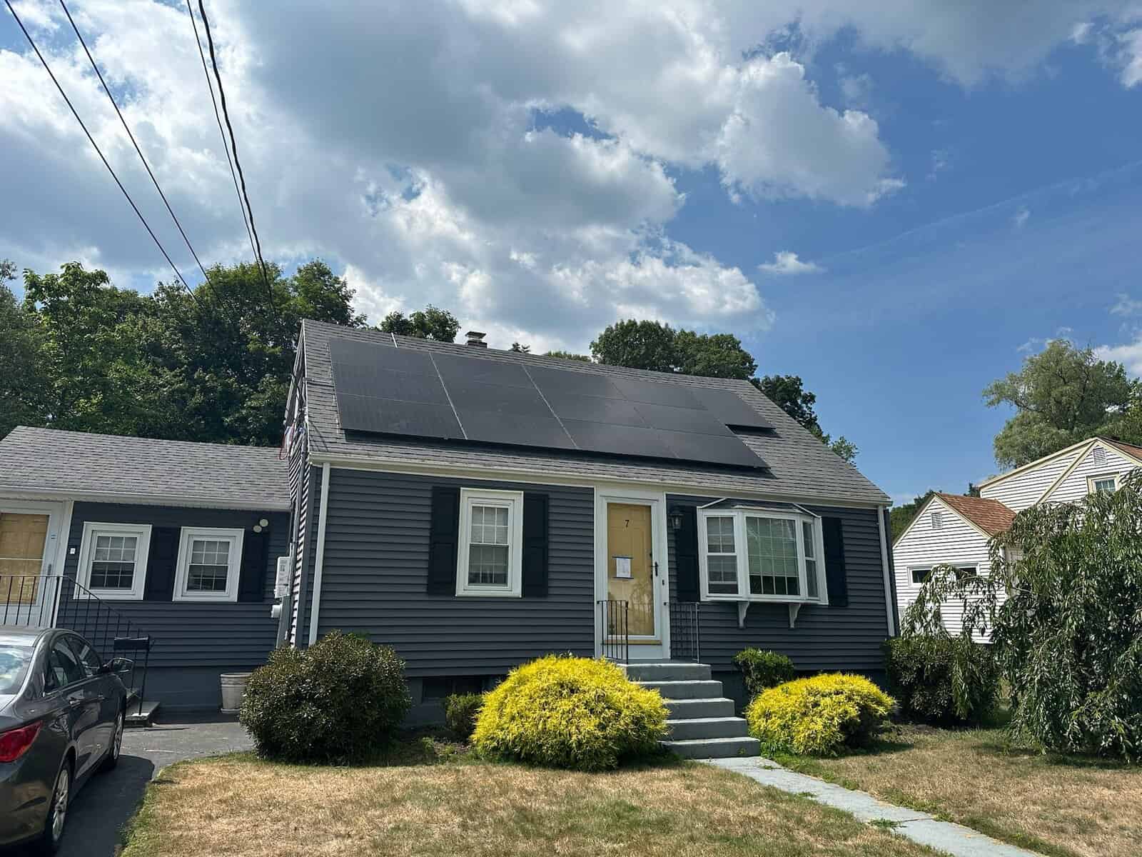 Gray single-family home with black solar panels on the roof, delivering clean energy and lowering monthly electric bills.
