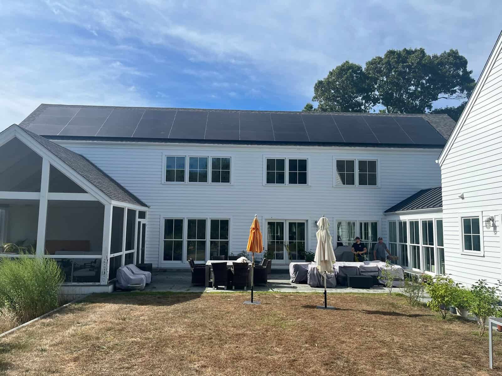 Large modern white home with rooftop solar panels spanning the entire upper roofline, maximizing clean energy production and long-term savings.