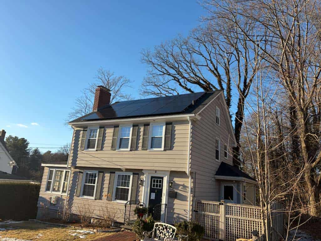 A clean, professional rooftop solar array capturing full sun on a clear day. The dark panels are neatly aligned along the main roofline, converting daylight into dependable electricity and helping this home reduce energy costs with a simple, low-profile system.