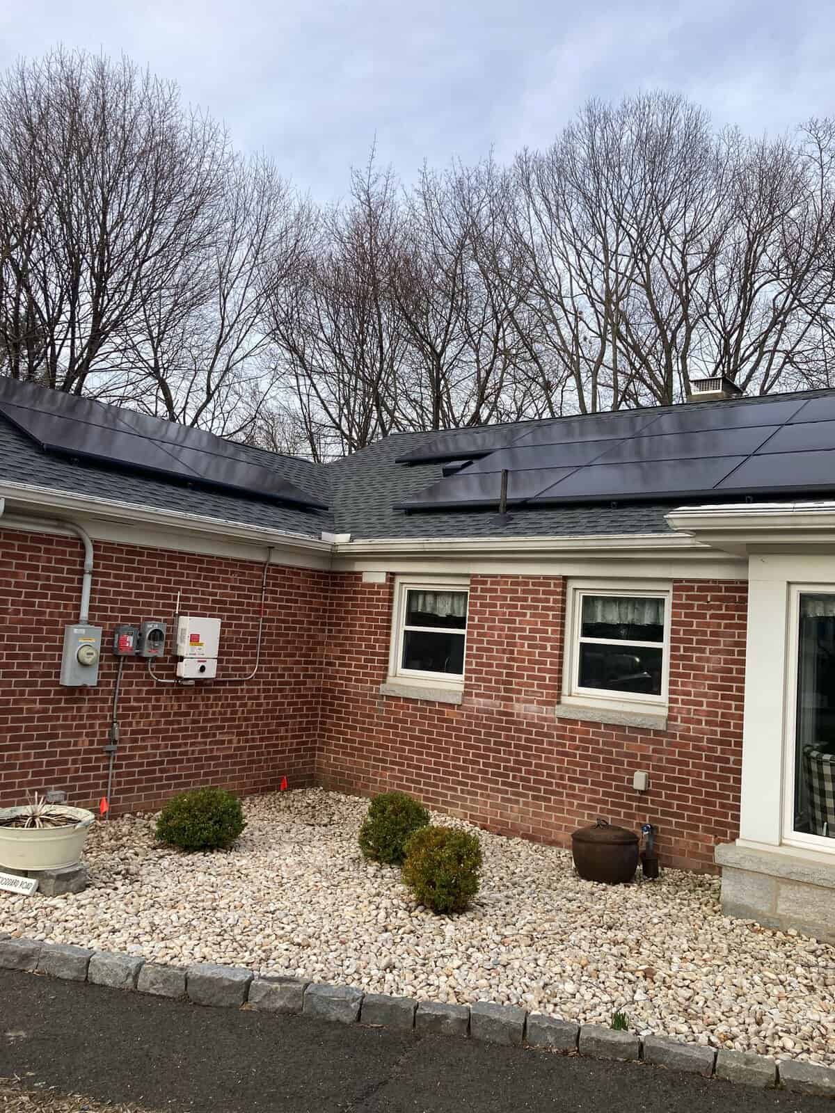 Solar panels installed on a residential roof with a clear sky and leafless trees in the background, demonstrating a home solar energy system for sustainable power generation.