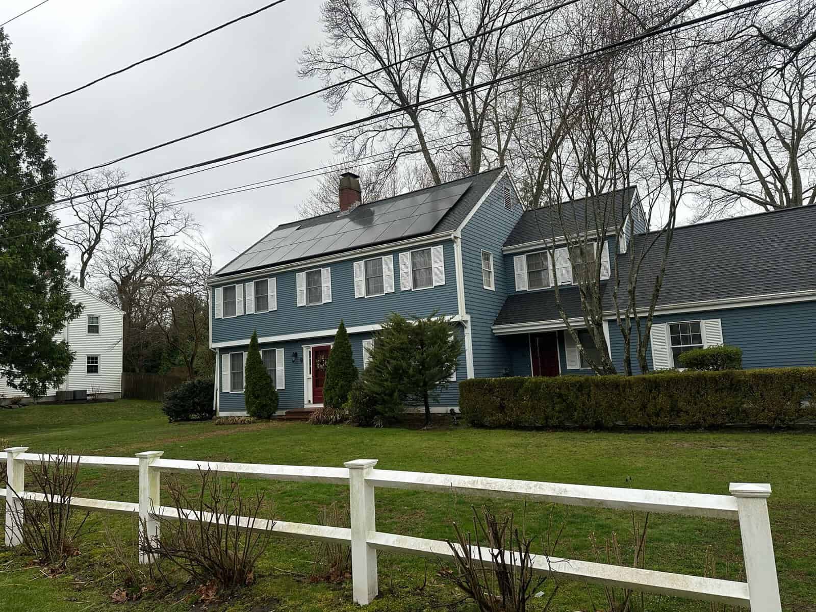 Solar panel installation on the roof of a blue house, residential solar energy system, eco-friendly home with renewable energy source, modern rooftop solar array, sustainable living renewable energy solution.