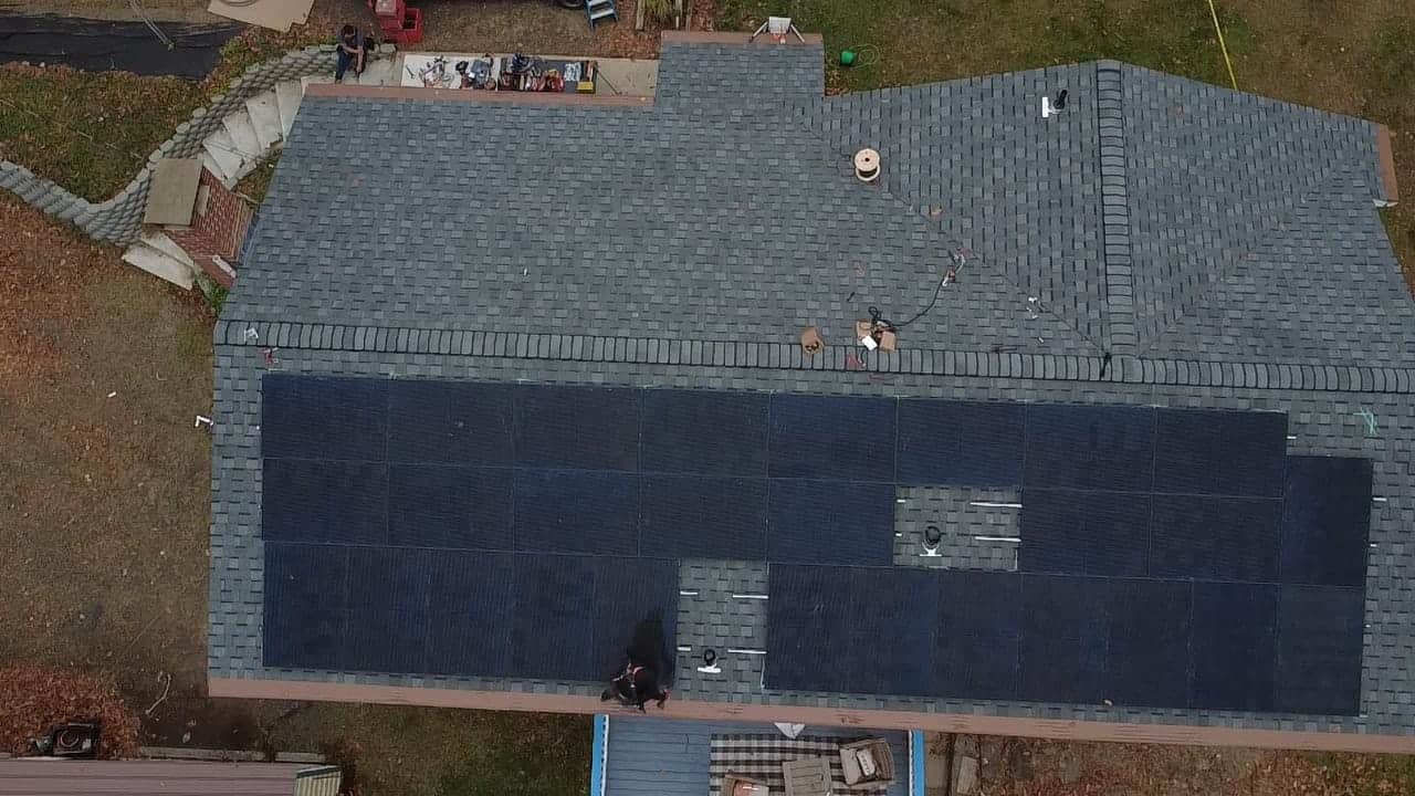 Aerial view of a residential roof with a neatly installed solar panel system. The rooftop solar array is laid out to maximize usable space while maintaining clear access points, showcasing a clean, professional solar installation on an asphalt shingle roof.