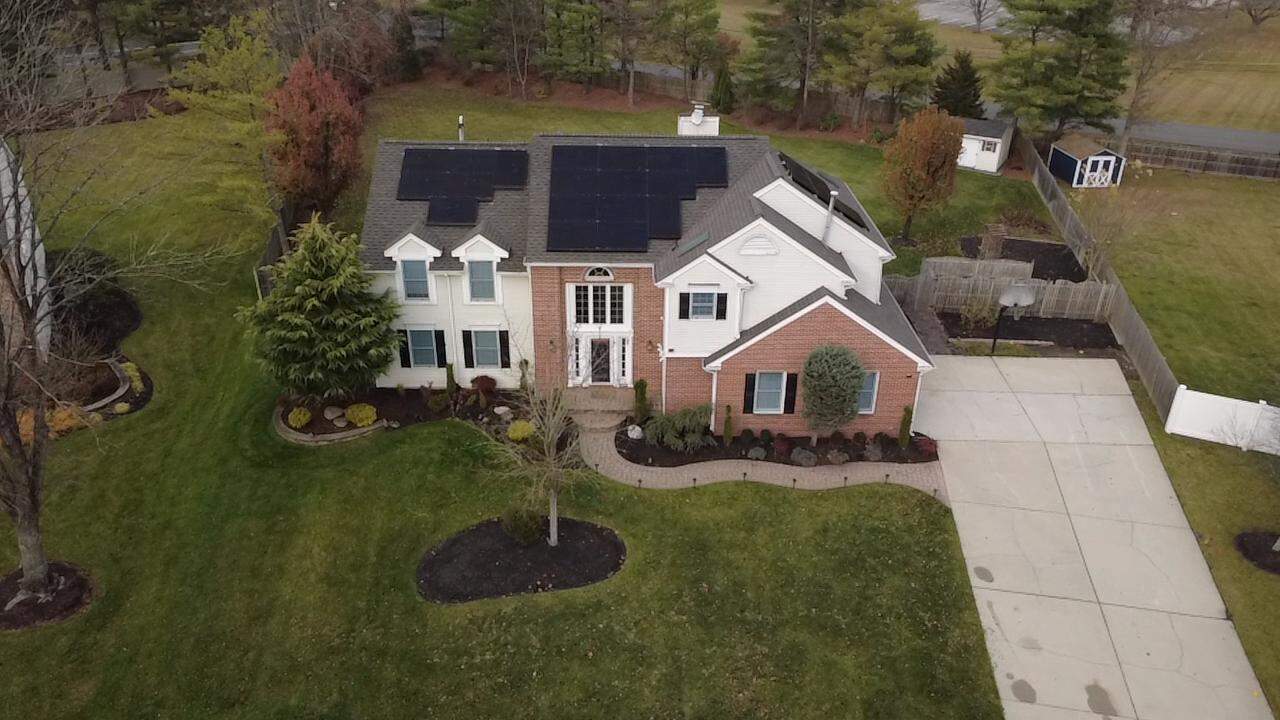 Aerial front-facing view of a New England home with a thoughtfully placed rooftop solar array, following the roof’s geometry for a clean, symmetrical appearance while maximizing usable roof space and curb appeal.