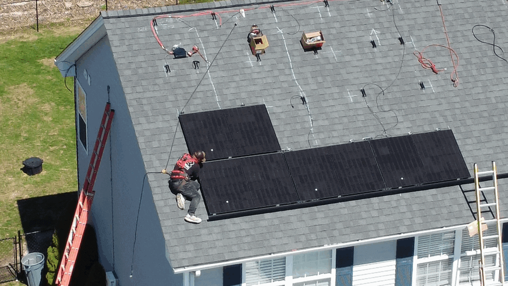 Solar panel installation on residential roof for sustainable energy generation, worker installing photovoltaic panels, rooftop solar system for renewable power, clean energy solar panels on home roof, roof-mounted solar power system installation in progress.
